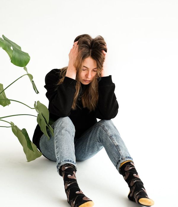 A person sitting in a calm, meditative pose in a minimalist room with soft lighting.